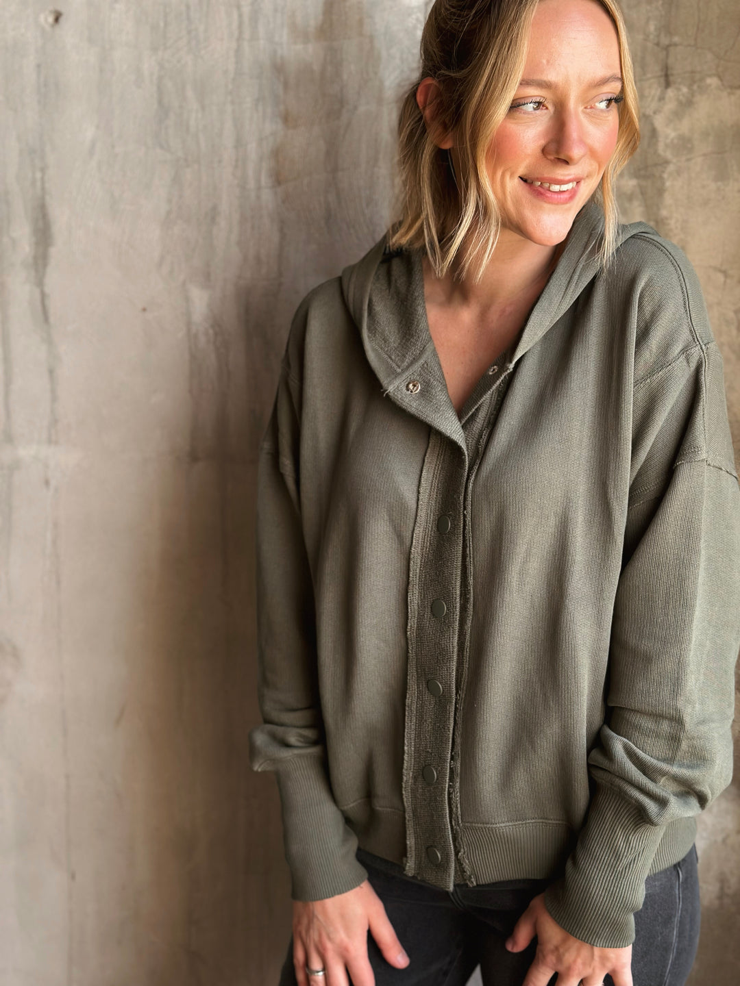 Woman wearing a green jacket against a textured wall