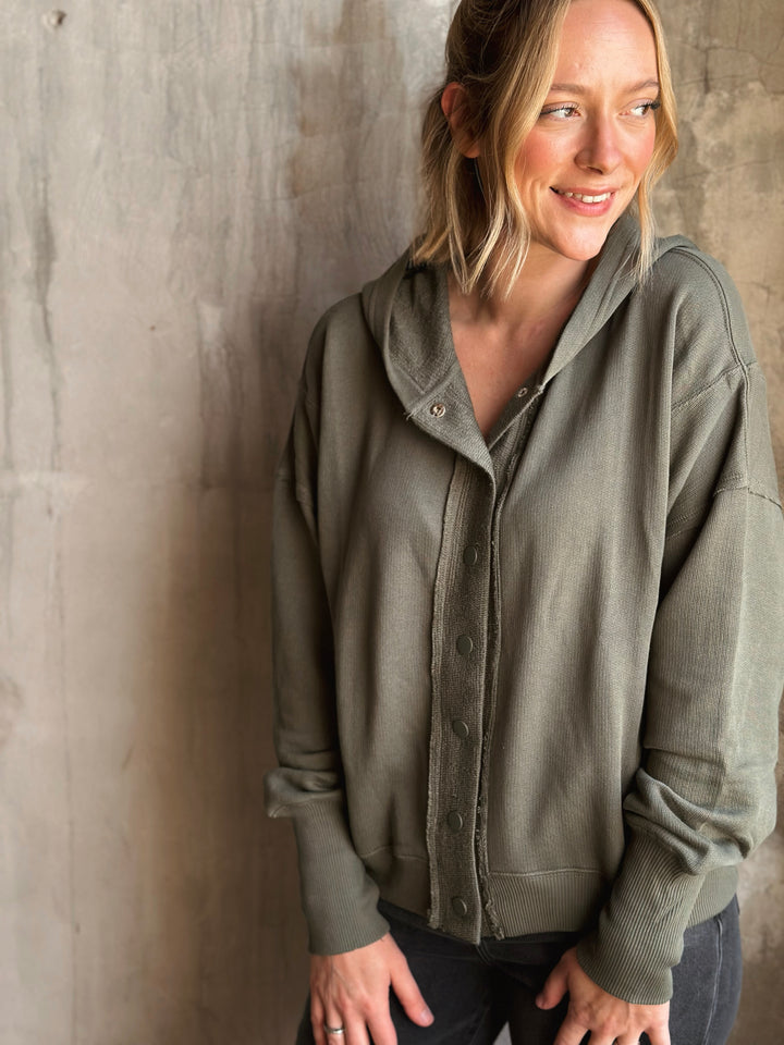 Woman wearing a green jacket against a textured wall