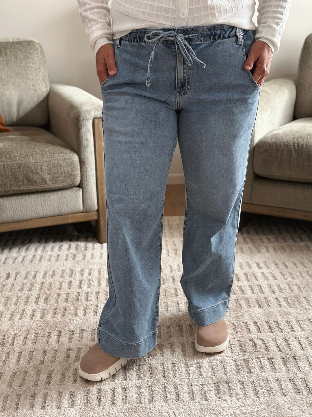 Person wearing blue jeans standing in a living room.