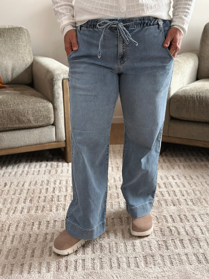 Person wearing blue jeans standing in a living room.