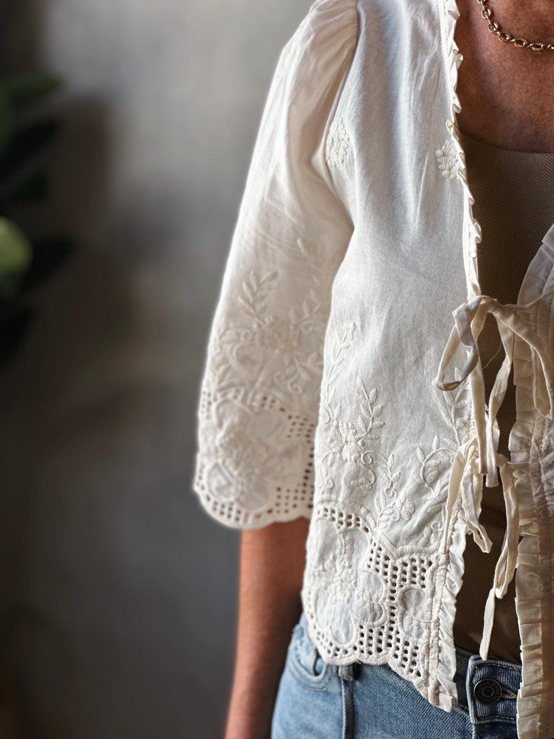 Close-up of a person wearing a white embroidered blouse with a blurred background