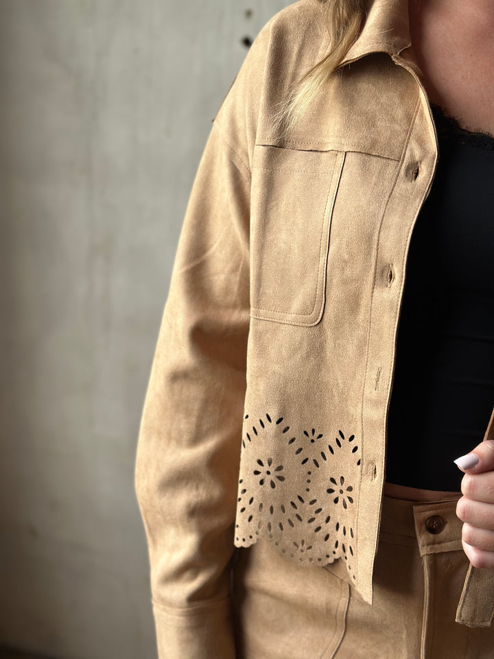 Close-up of the laser-cut eyelet hem on a tan suede-look shirt jacket