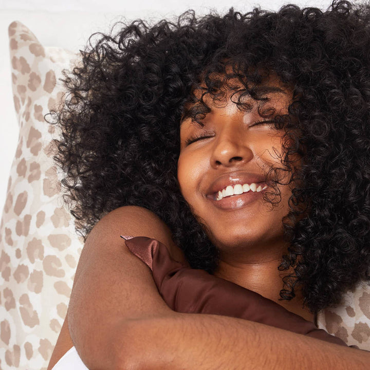 Woman with curly hair smiling on a patterned pillow