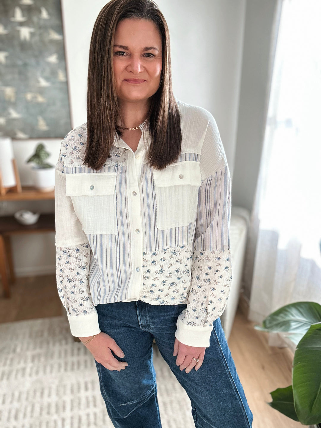 Woman wearing a patterned blouse and jeans indoors