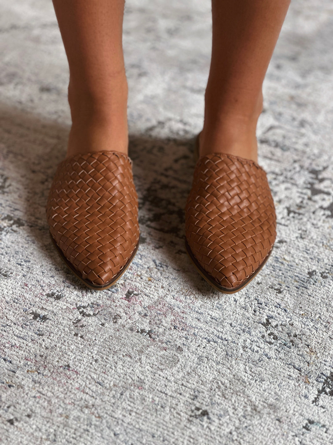 Brown woven shoes on a textured surface.