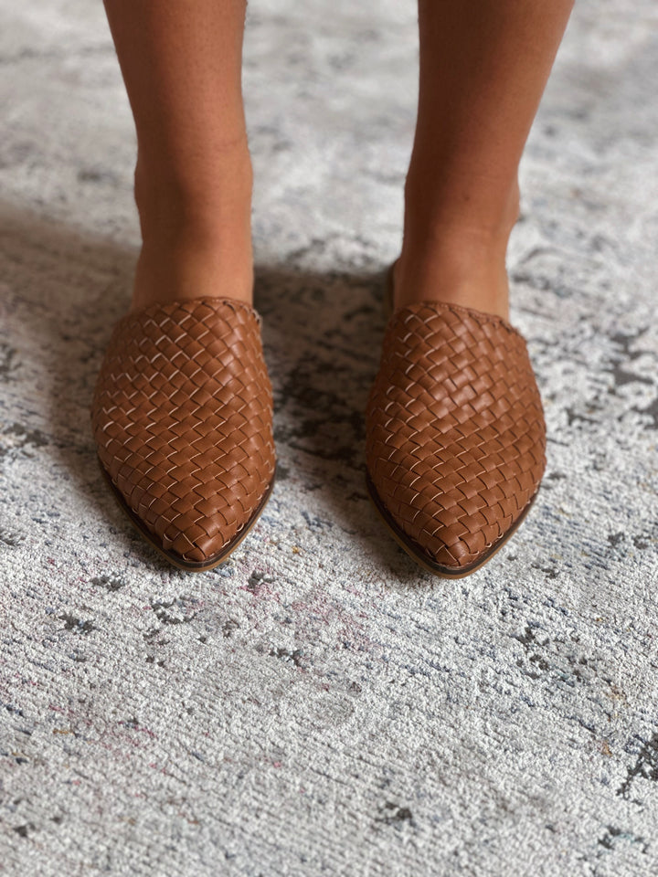 Brown woven shoes on a textured surface.