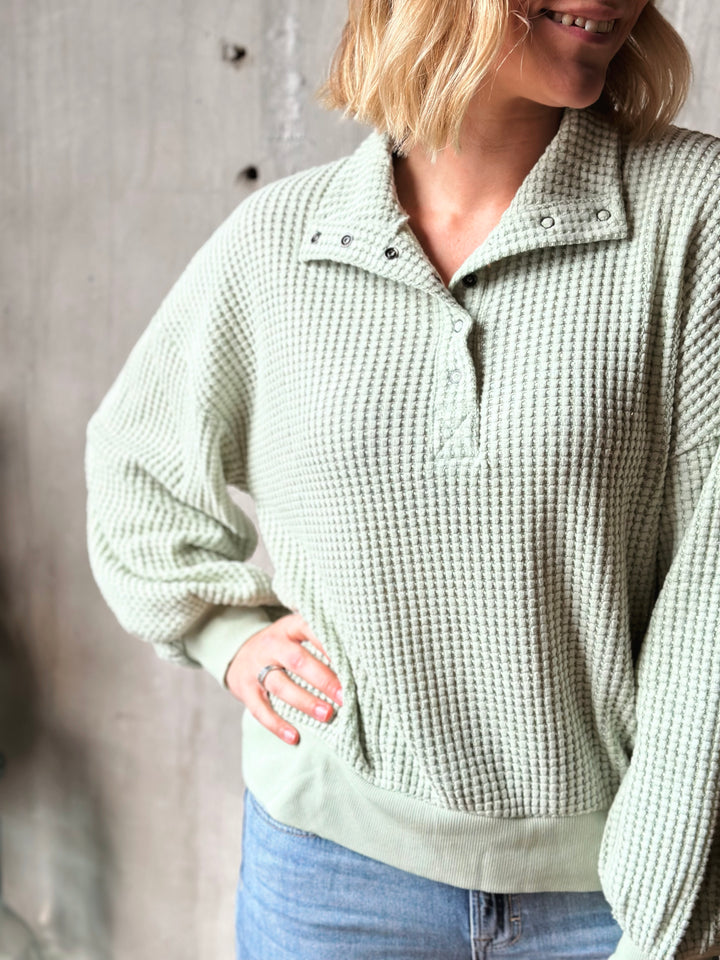 Person wearing a textured light green sweater with a neutral background
