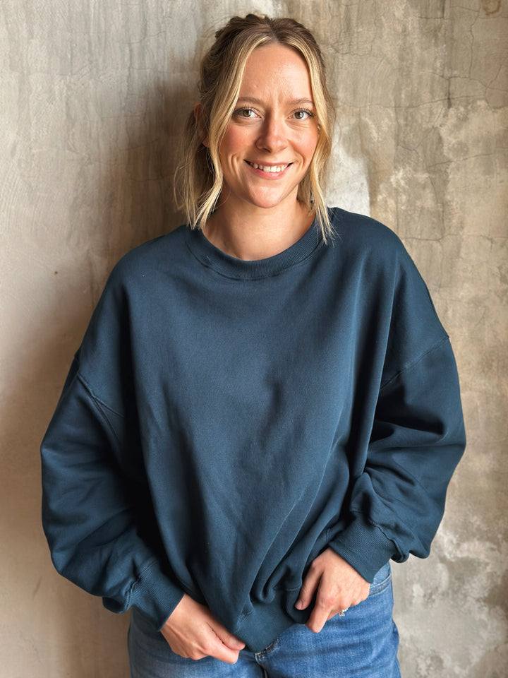 Person wearing a blue sweatshirt against a textured wall