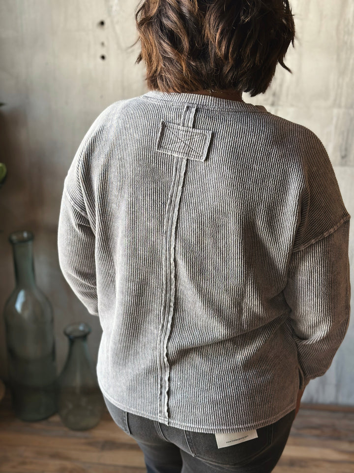 Person wearing a gray corduroy shirt with a neutral background