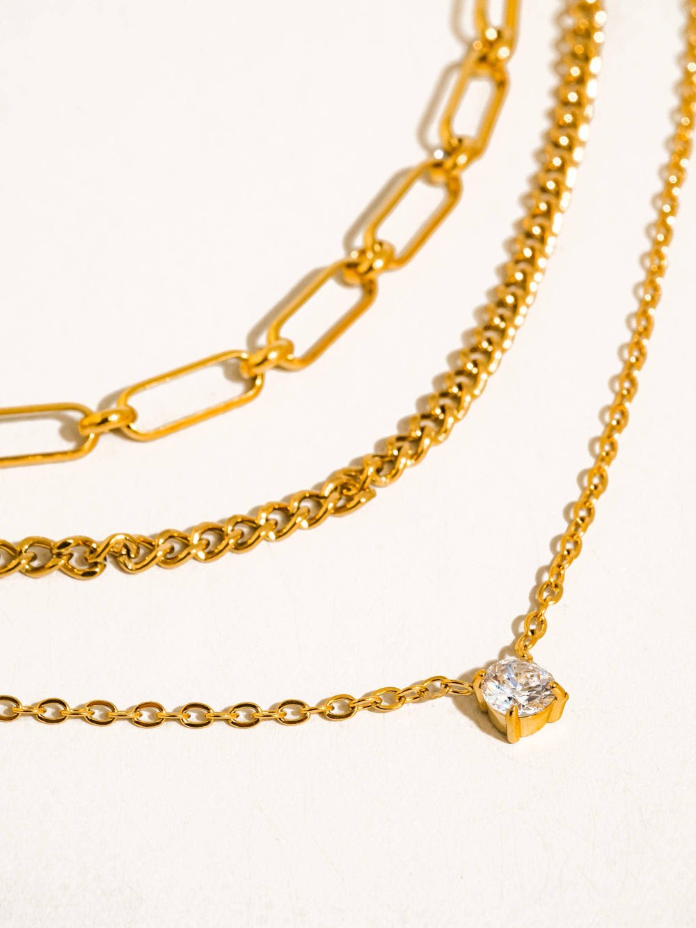 Three gold chains with varying designs on a white background