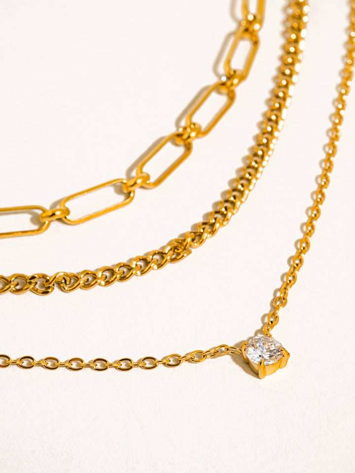 Three gold chains with varying designs on a white background