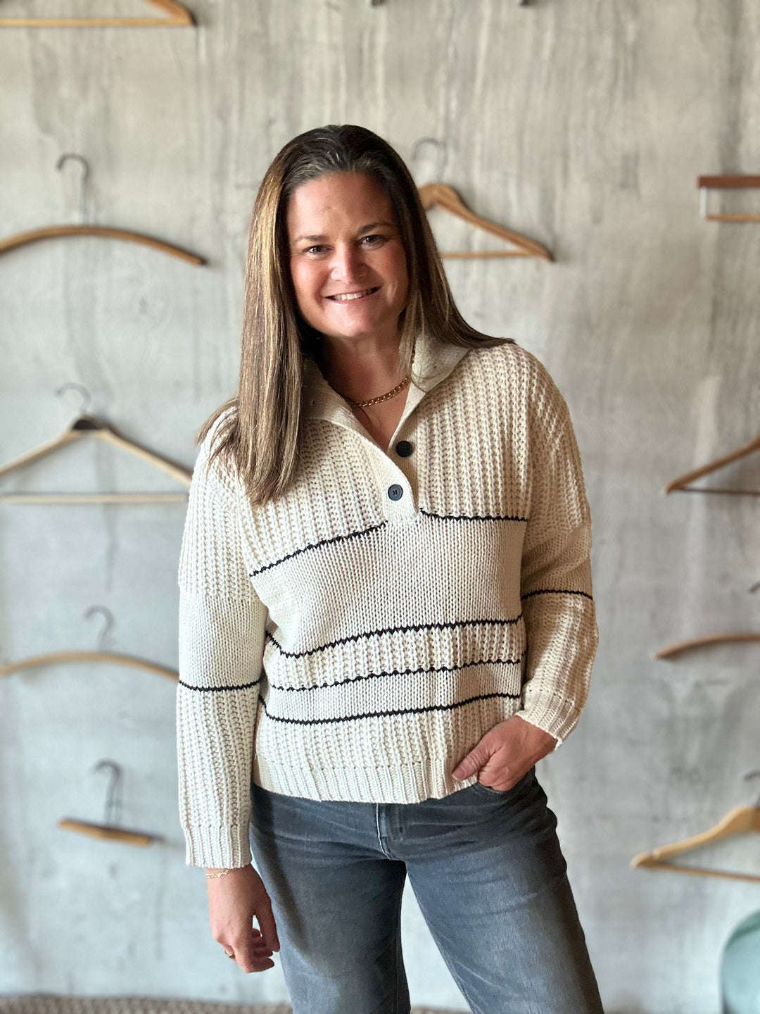 Woman in a cream collared sweater and jeans, angled view