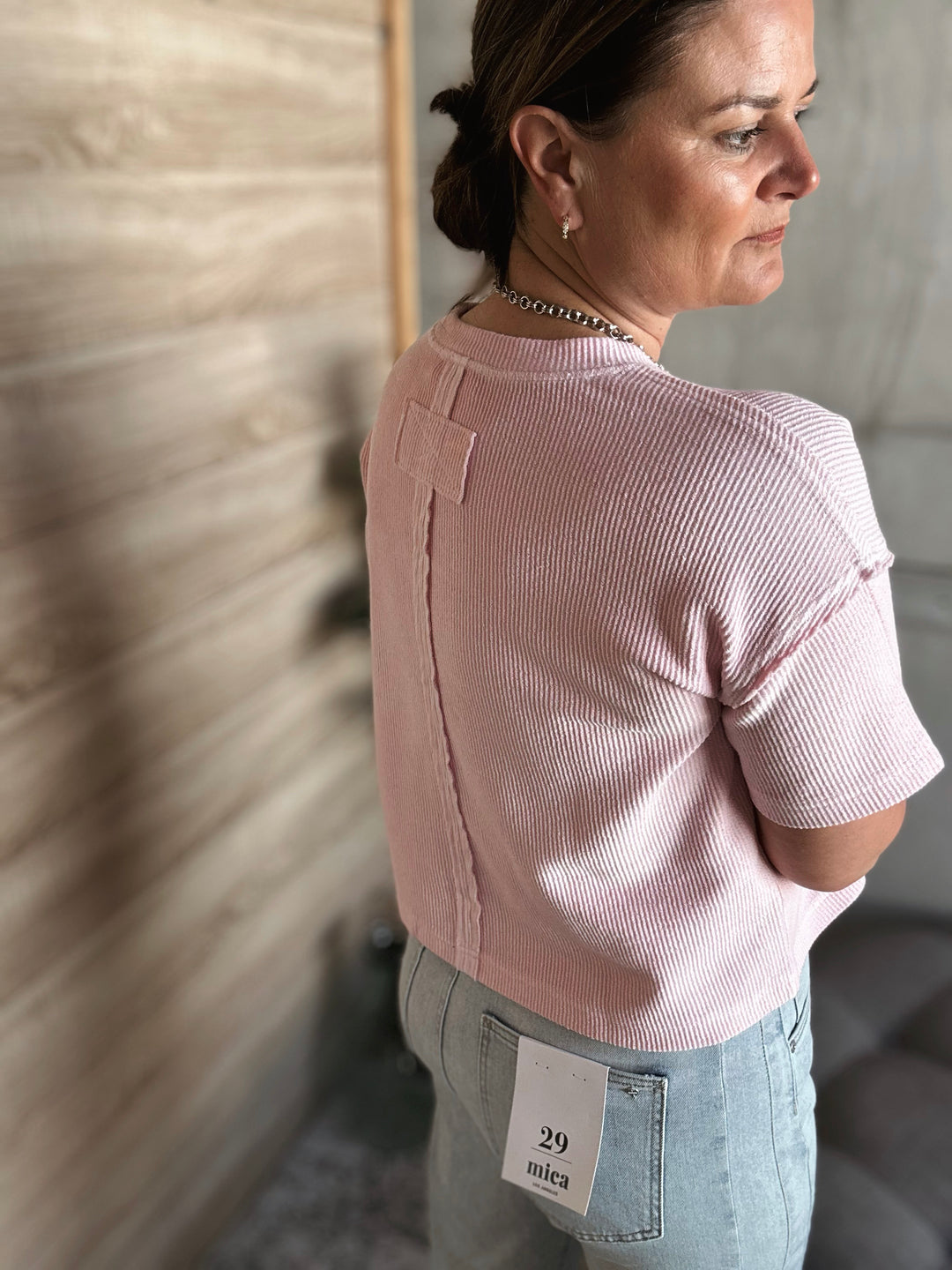 A woman wearing a textured light pink short sleeved shirt.