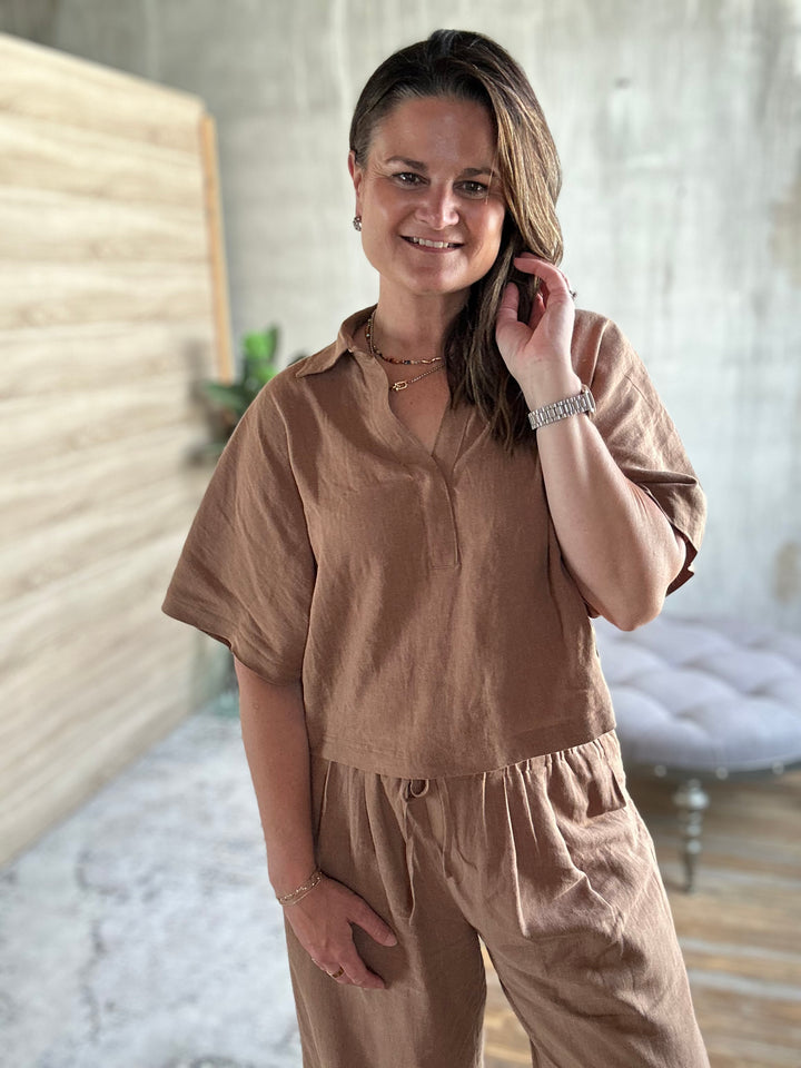 Woman wearing a brown outfit in a neutral setting.