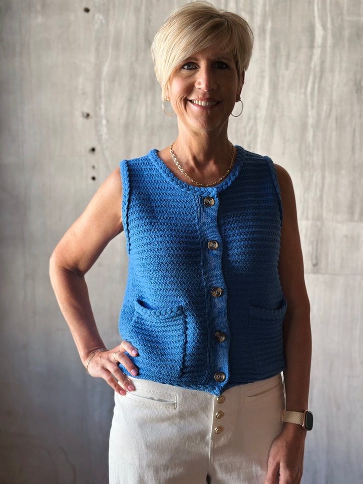 Front view solid blue sleeveless sweater knit vest, with a button front closure and functional front pockets. 