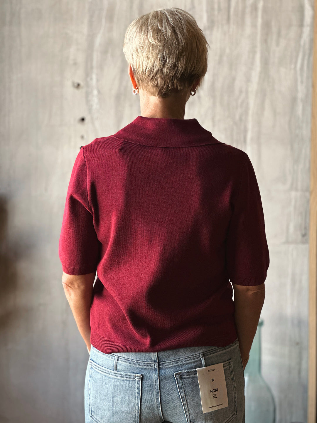 Person wearing a burgundy shirt with a wooden background