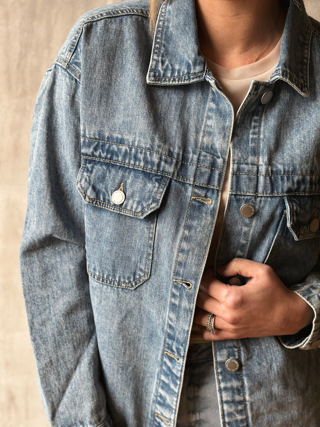 Close-up of a person wearing a light blue denim jacket on a neutral background
