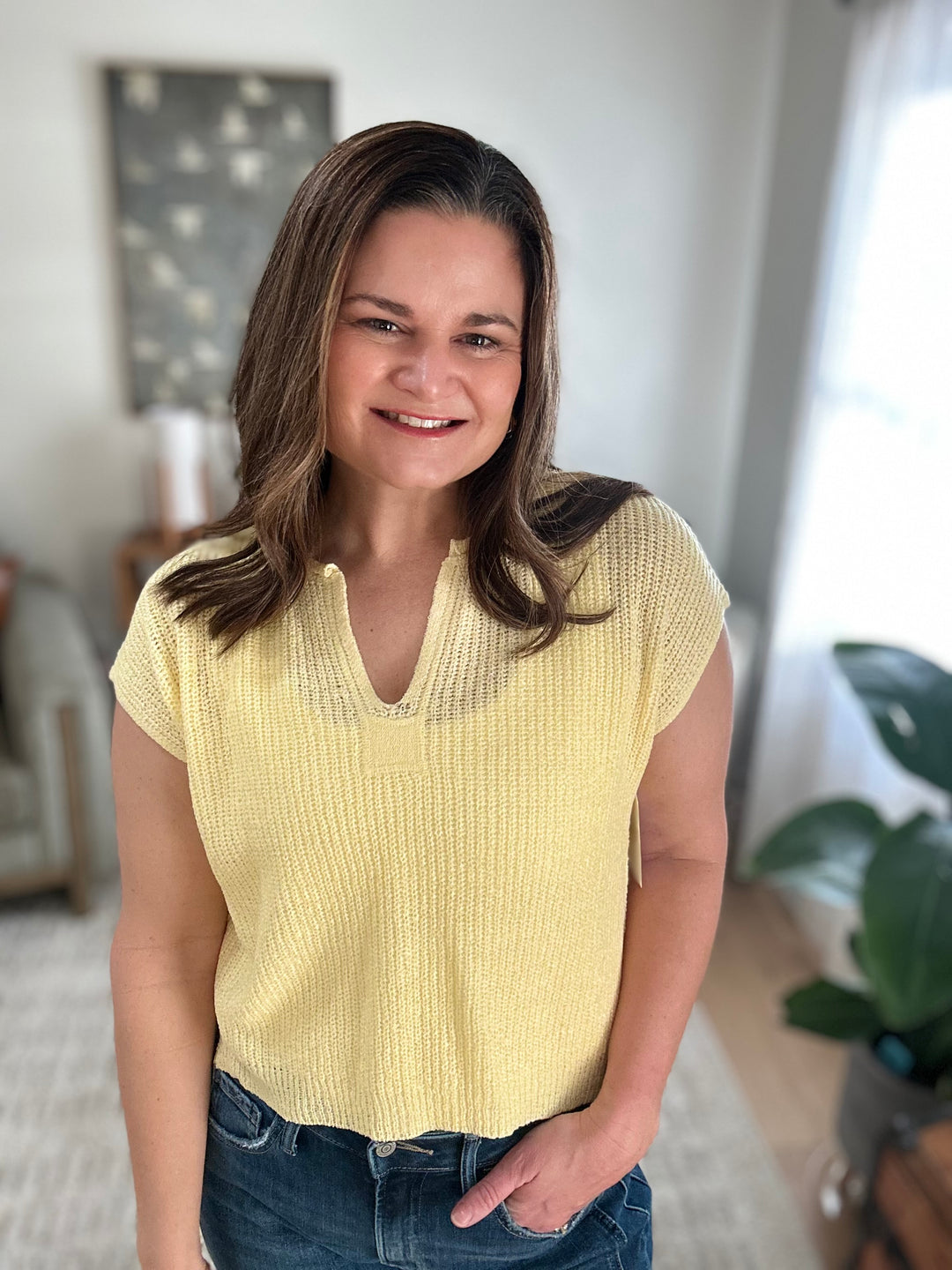 Woman wearing a yellow knitted top in a casual indoor setting