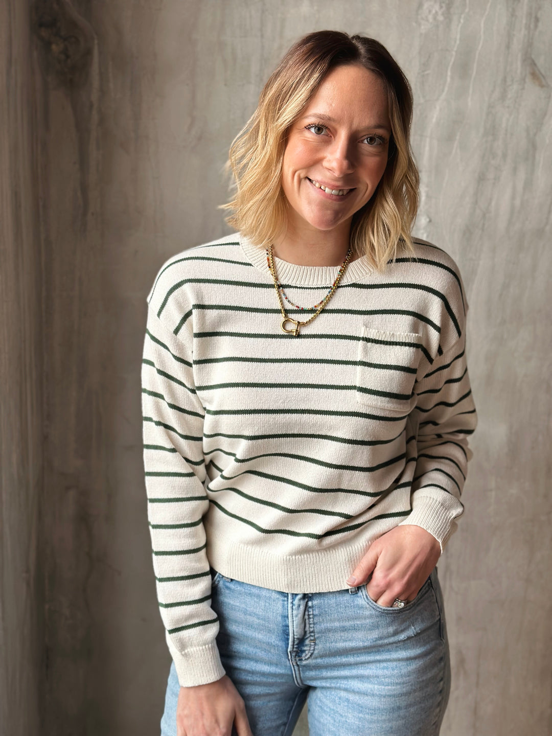 Woman wearing a striped sweater and jeans against a neutral background
