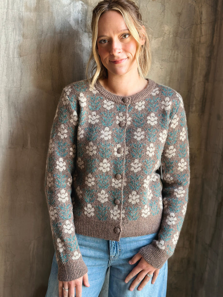 Woman wearing a floral-patterned sweater against a textured wall.