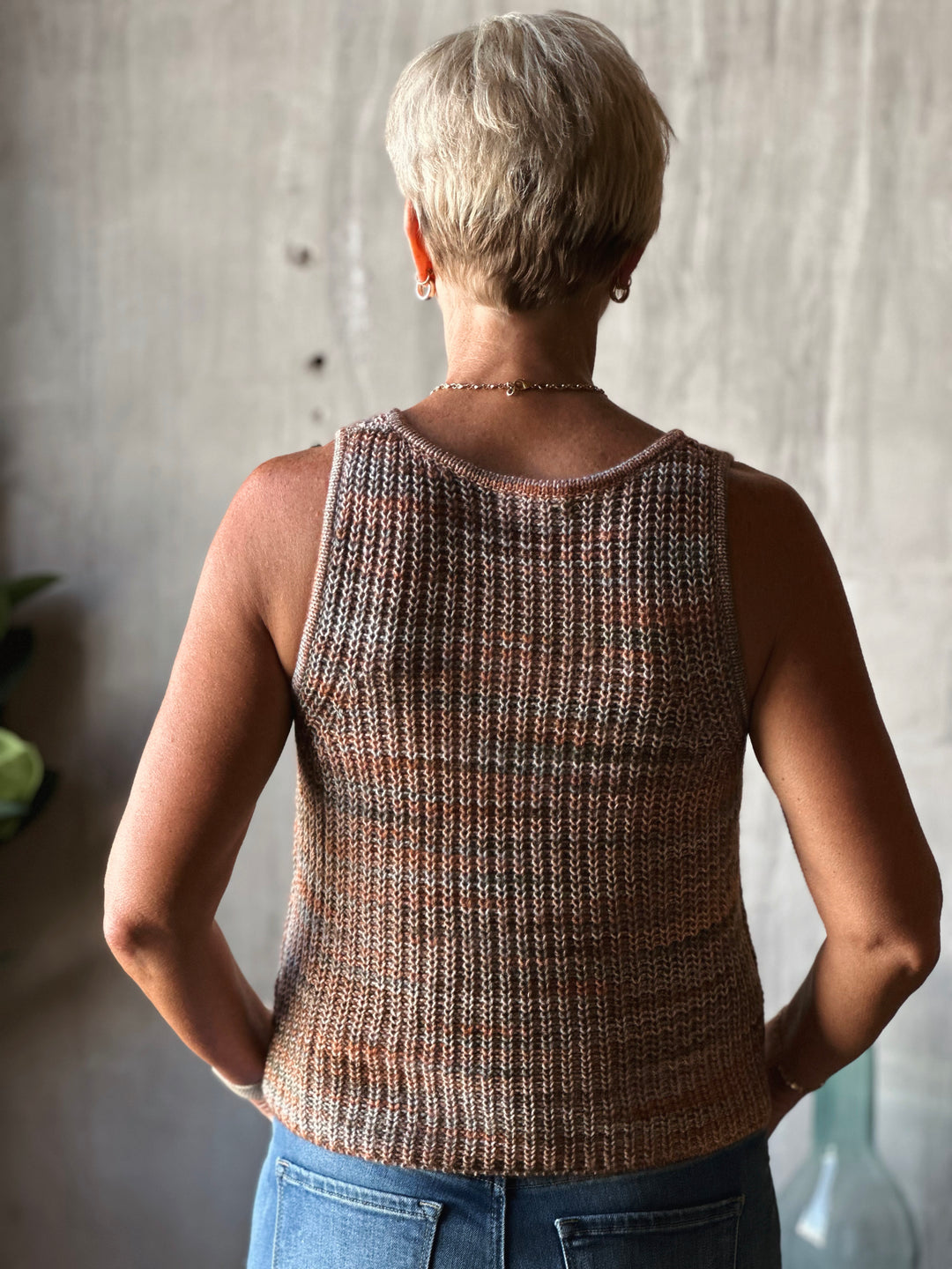 Person wearing a brown knitted tank top with a neutral background