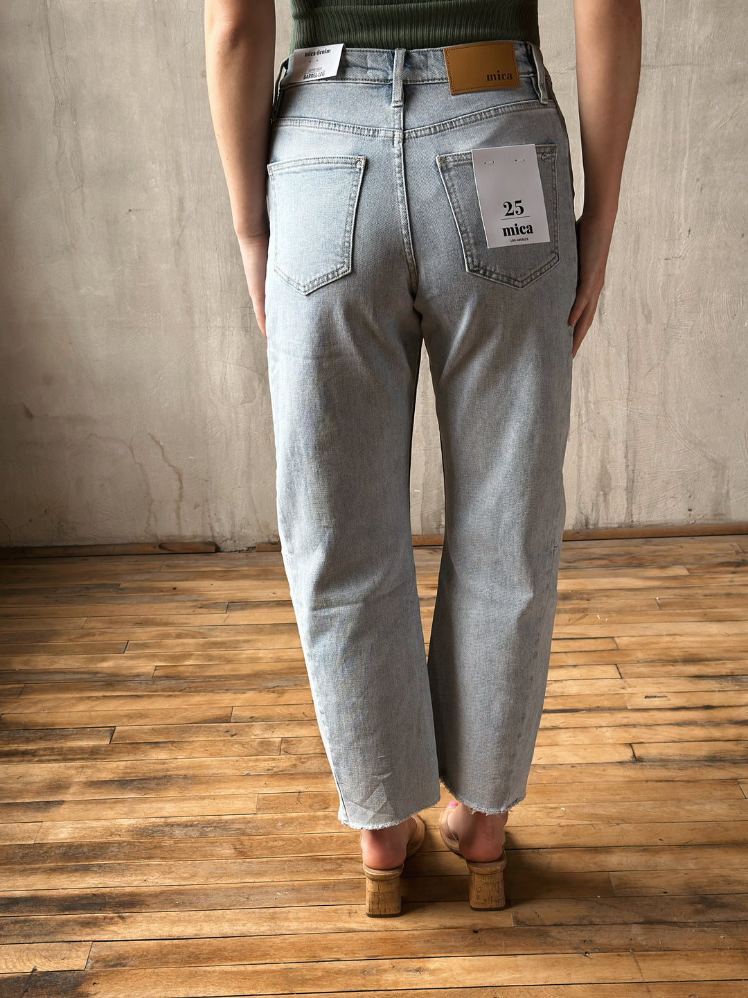 Person wearing light blue jeans with a visible brand label on a wooden floor.