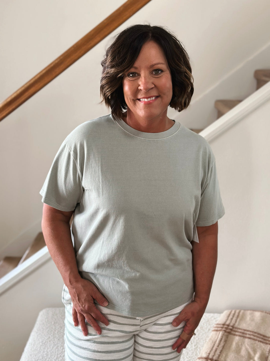 Woman wearing a light green t-shirt and striped pants 