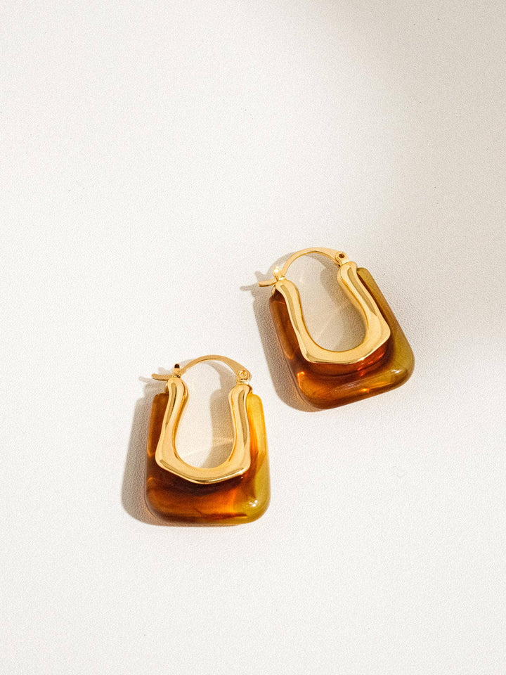 Pair of gold hoop earrings on a light beige background