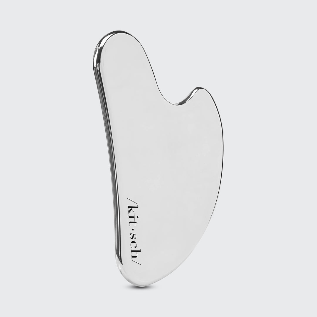 Silver gua sha tool with 'kitsch' branding on a light gray background