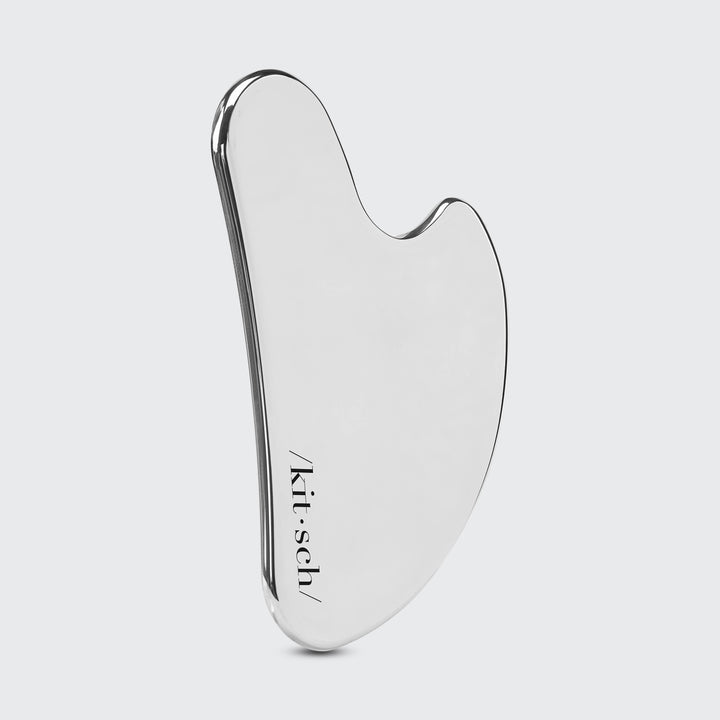 Silver gua sha tool with 'kitsch' branding on a light gray background