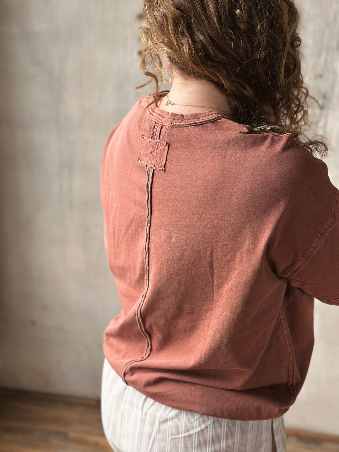 Person wearing a brown shirt with a neutral background