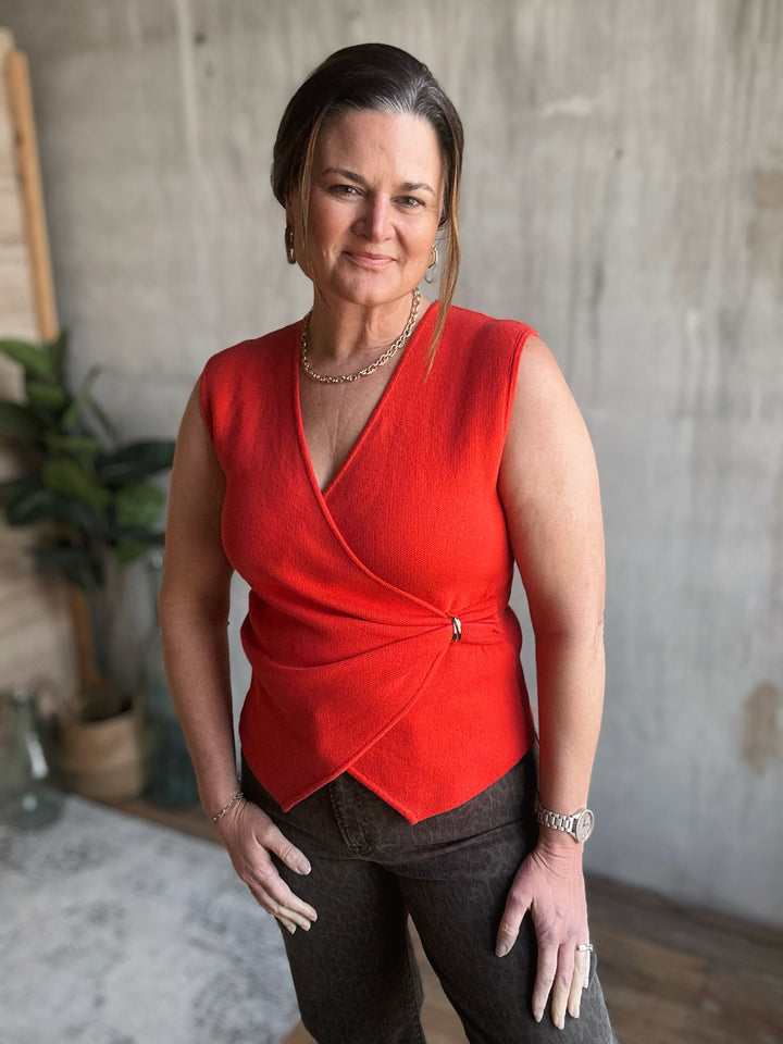 Woman wearing a red sleeveless top in an indoor setting.