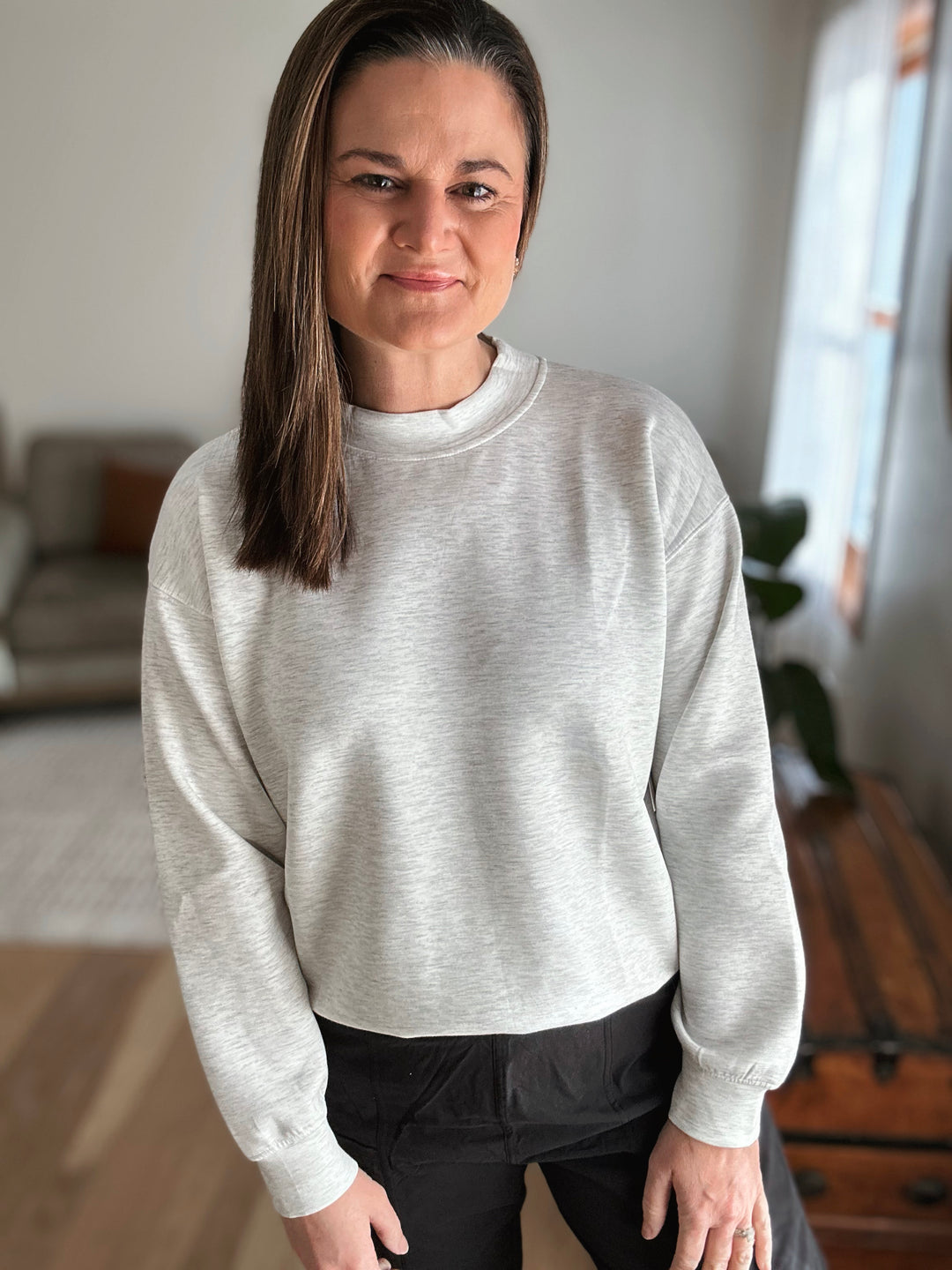Woman wearing a light gray sweater in an indoor setting