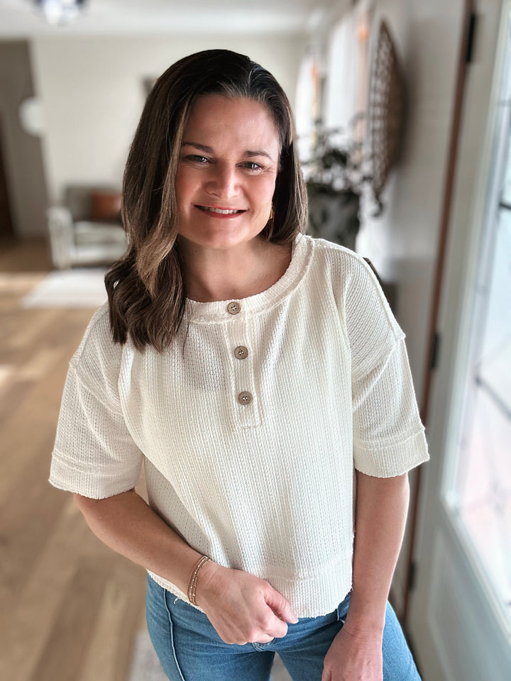 Woman wearing a white blouse with buttons in a home setting