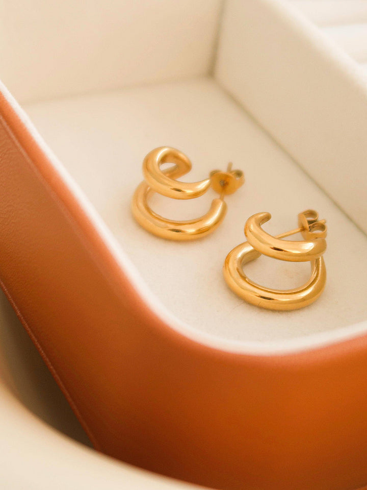 Gold hoop earrings on a beige cushion