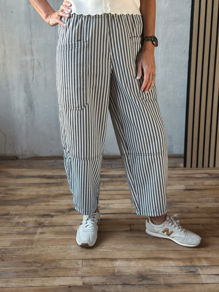 Person wearing striped pants and white sneakers on a wooden floor.