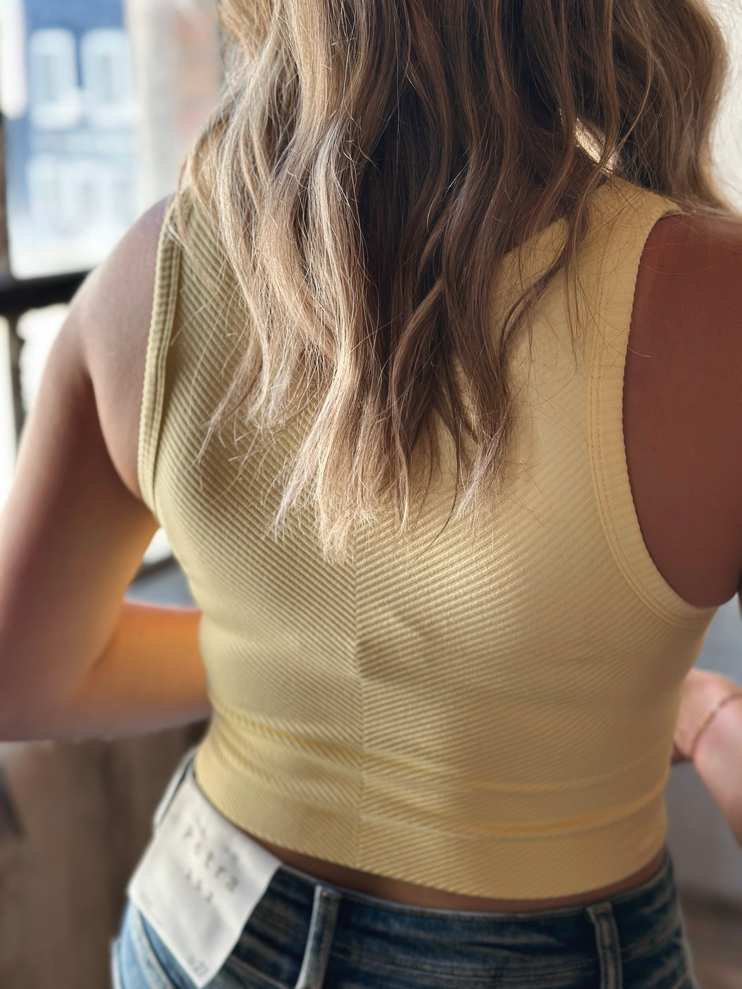 Person wearing a beige sleeveless top with a blurred background