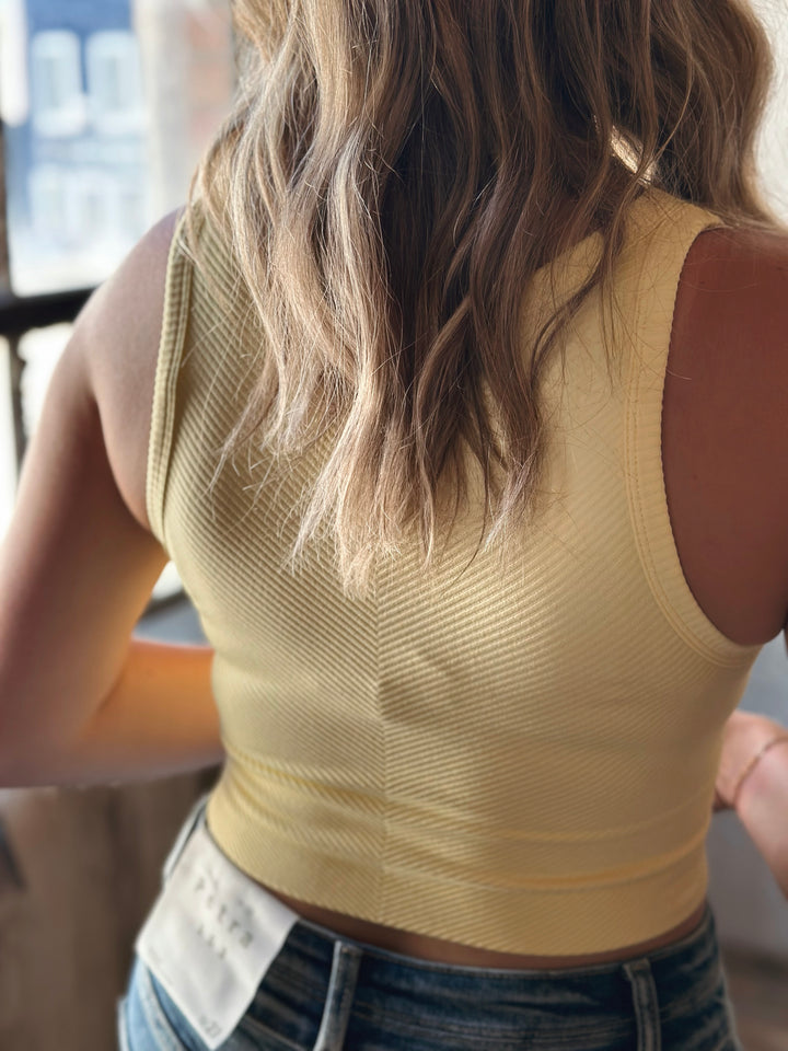 Person wearing a beige sleeveless top with a blurred background