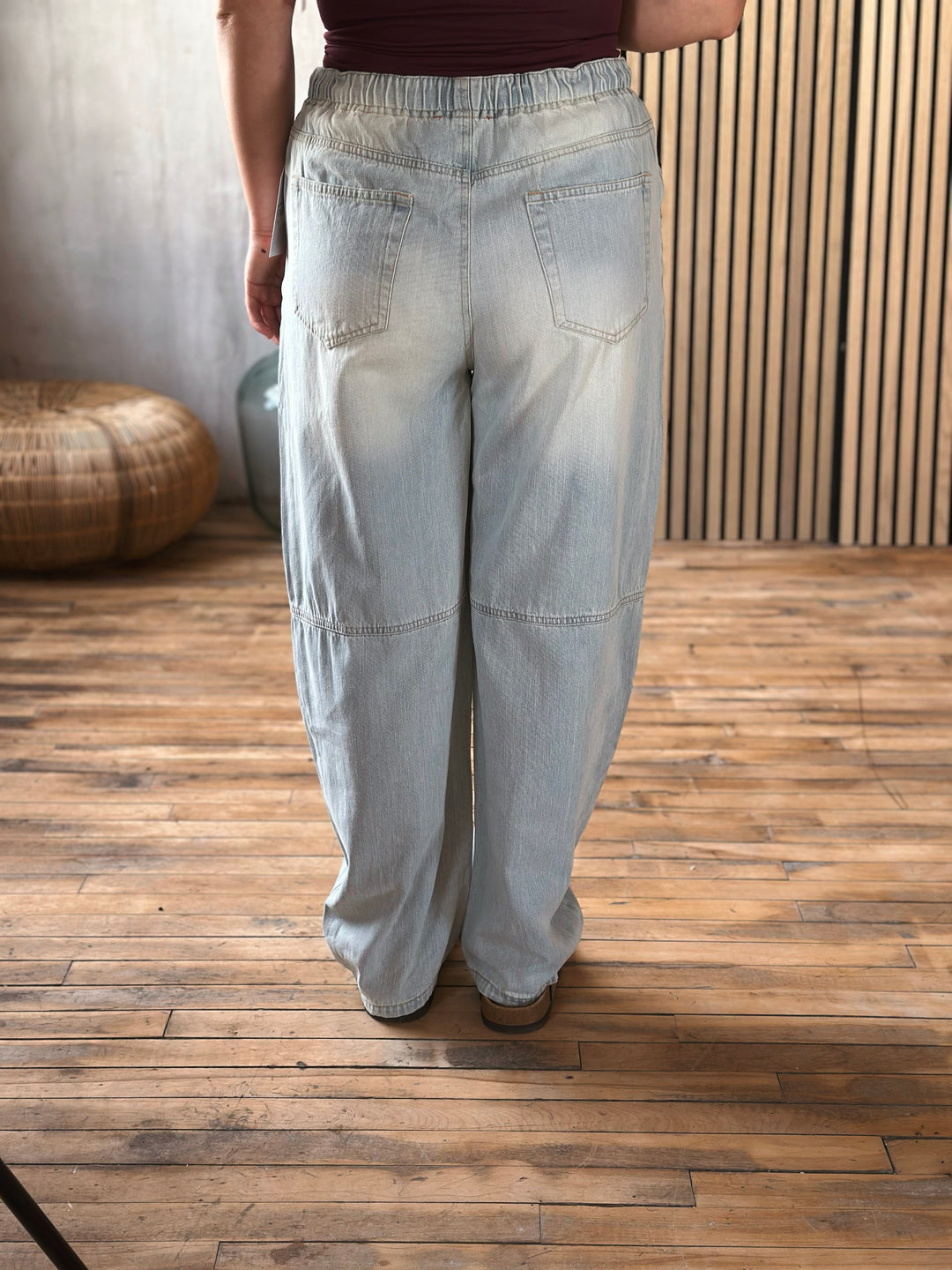 Person wearing light blue wide-leg pants on a wooden floor.