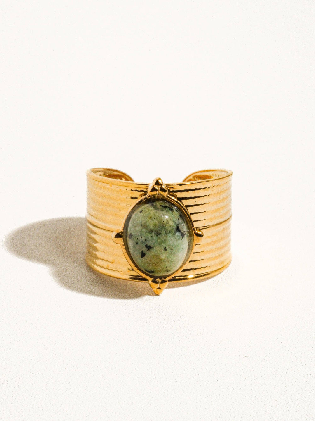 Gold ring with a green stone on a white background