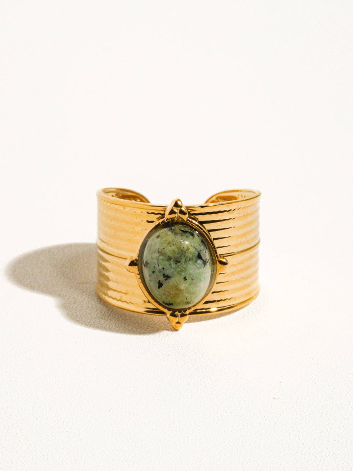Gold ring with a green stone on a white background