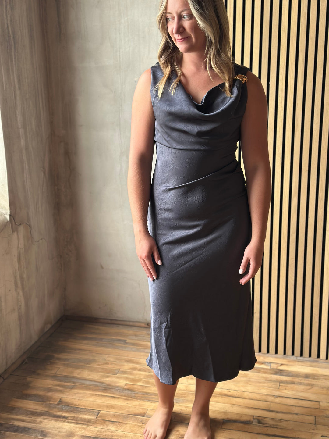 Woman wearing a slate gray satin cowl-neck midi dress