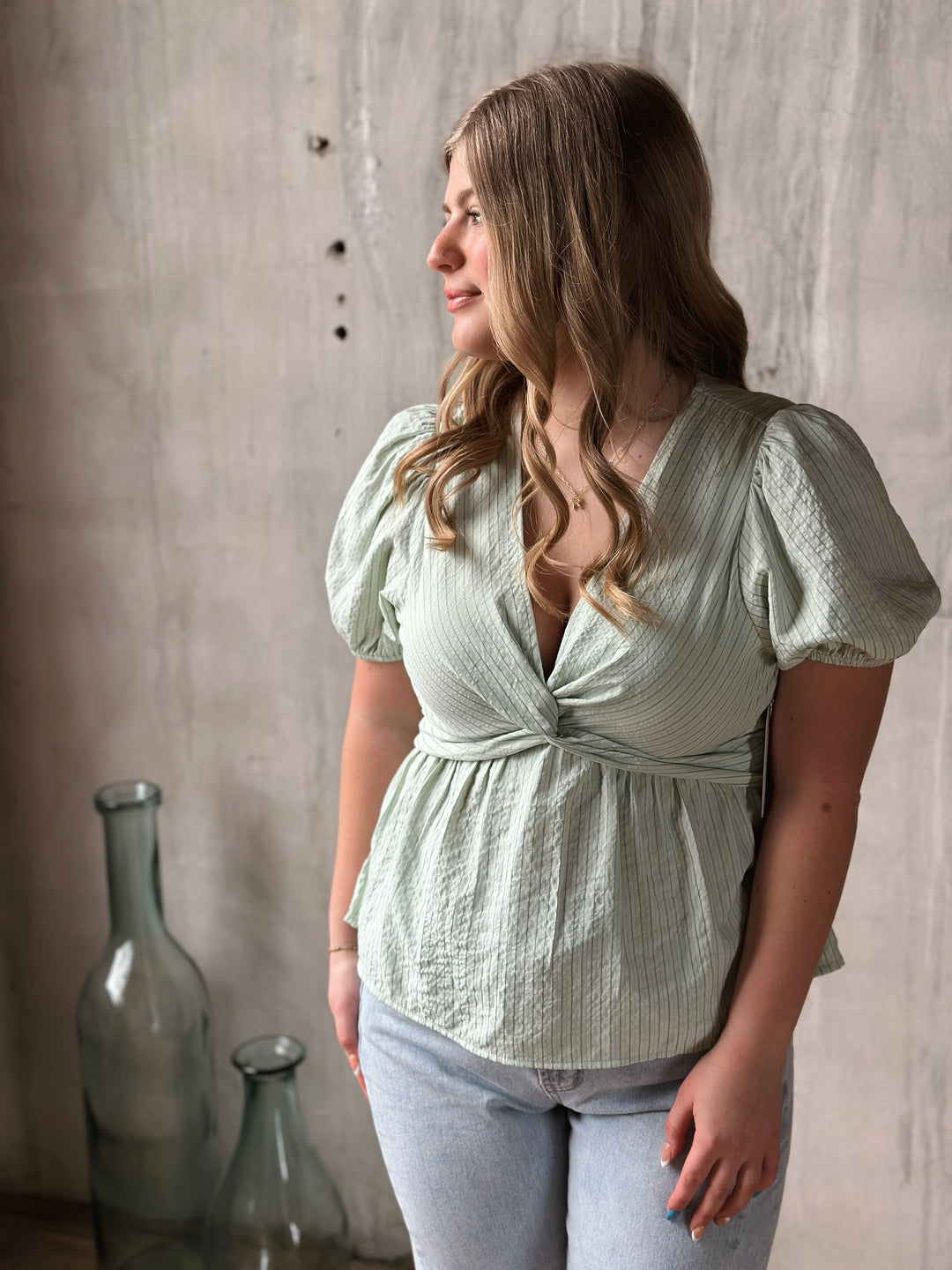 Woman wearing a light green blouse with puffed sleeves against a neutral background