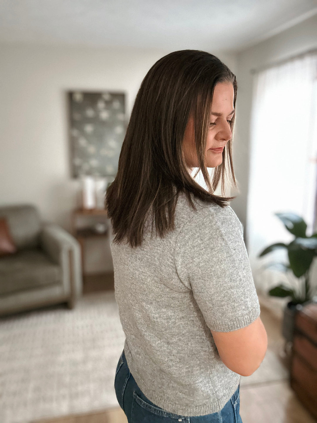 Woman wearing a gray sweater in a living room setting
