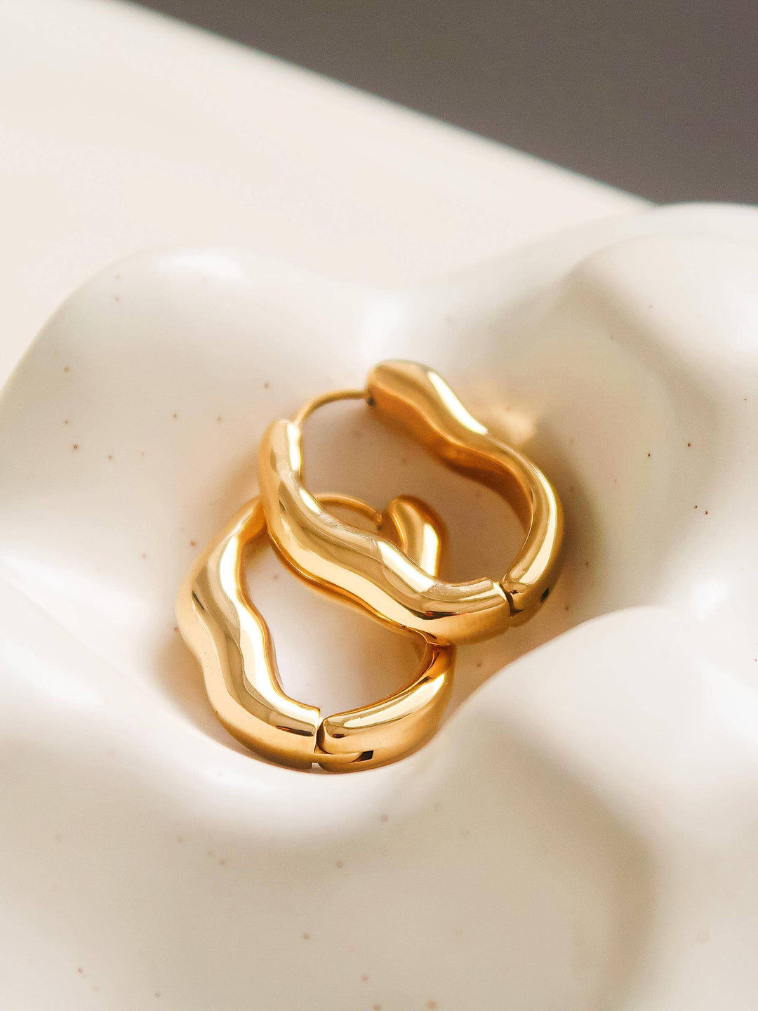 Gold hoop earrings on a textured white surface