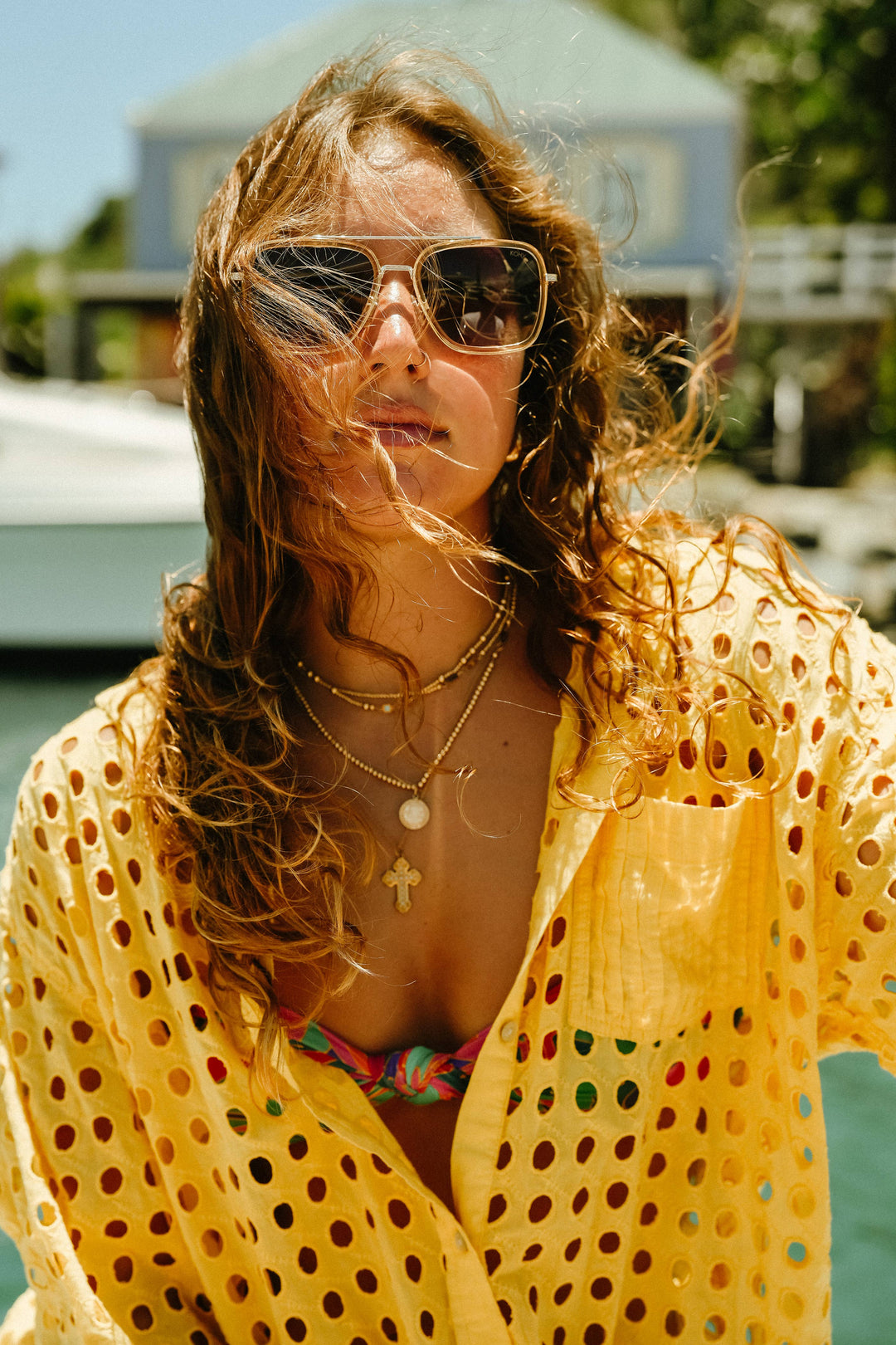 Woman wearing sunglasses and a yellow polka dot cover-up with a blurred background