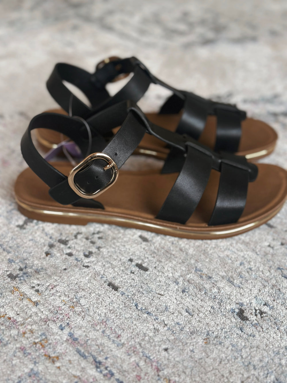 Black strappy sandals on a textured gray surface