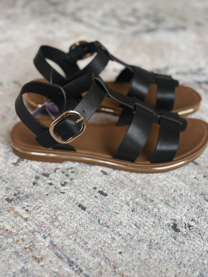 Black strappy sandals on a textured gray surface