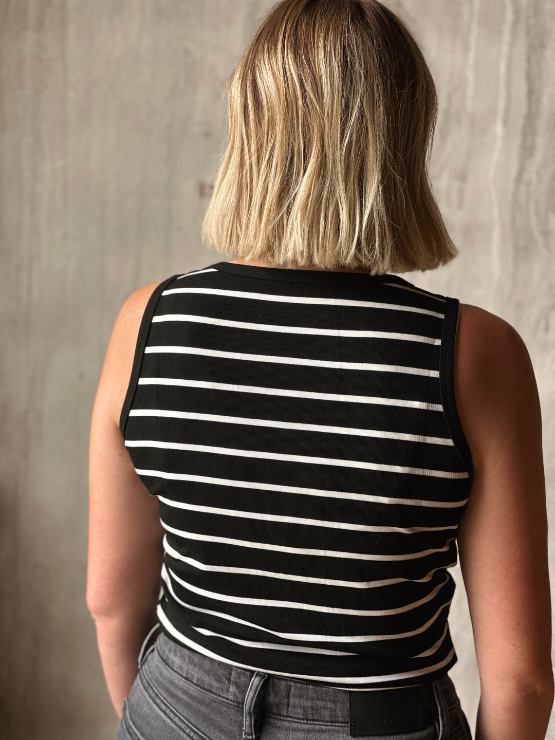 Person wearing a black and white striped sleeveless top against a neutral background