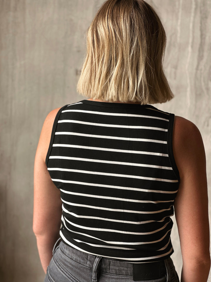 Person wearing a black and white striped sleeveless top against a neutral background